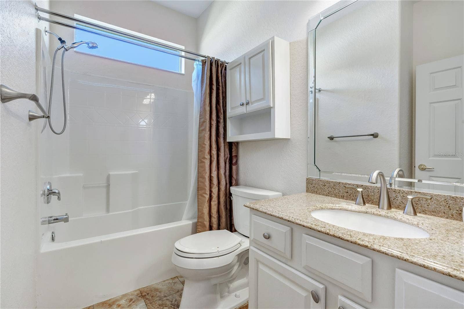 Full guest bathroom with tub and shower combination, vanity storage, and neutral finishes.