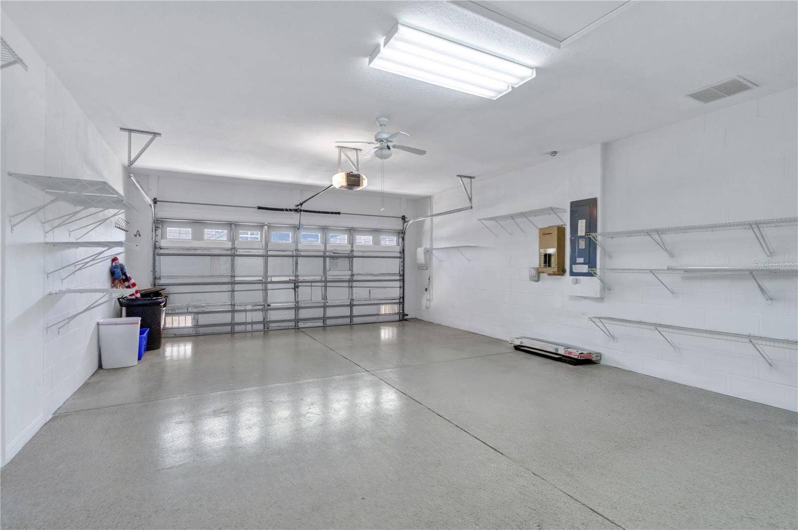 Spacious attached two-car garage with built-in storage shelving and room for vehicles and essentials.