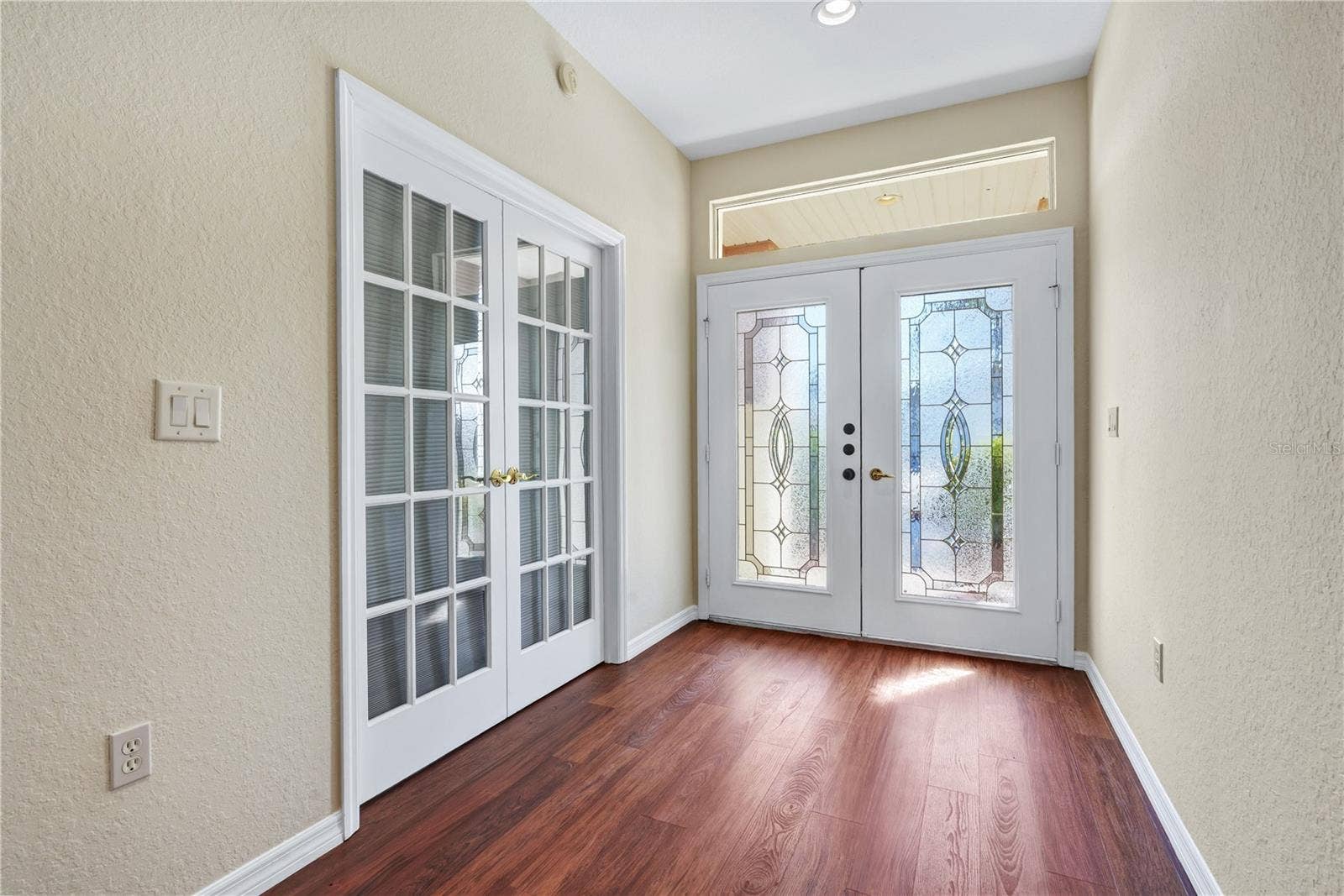 Bright entry foyer with French doors, attractive flooring, and a welcoming first impression.