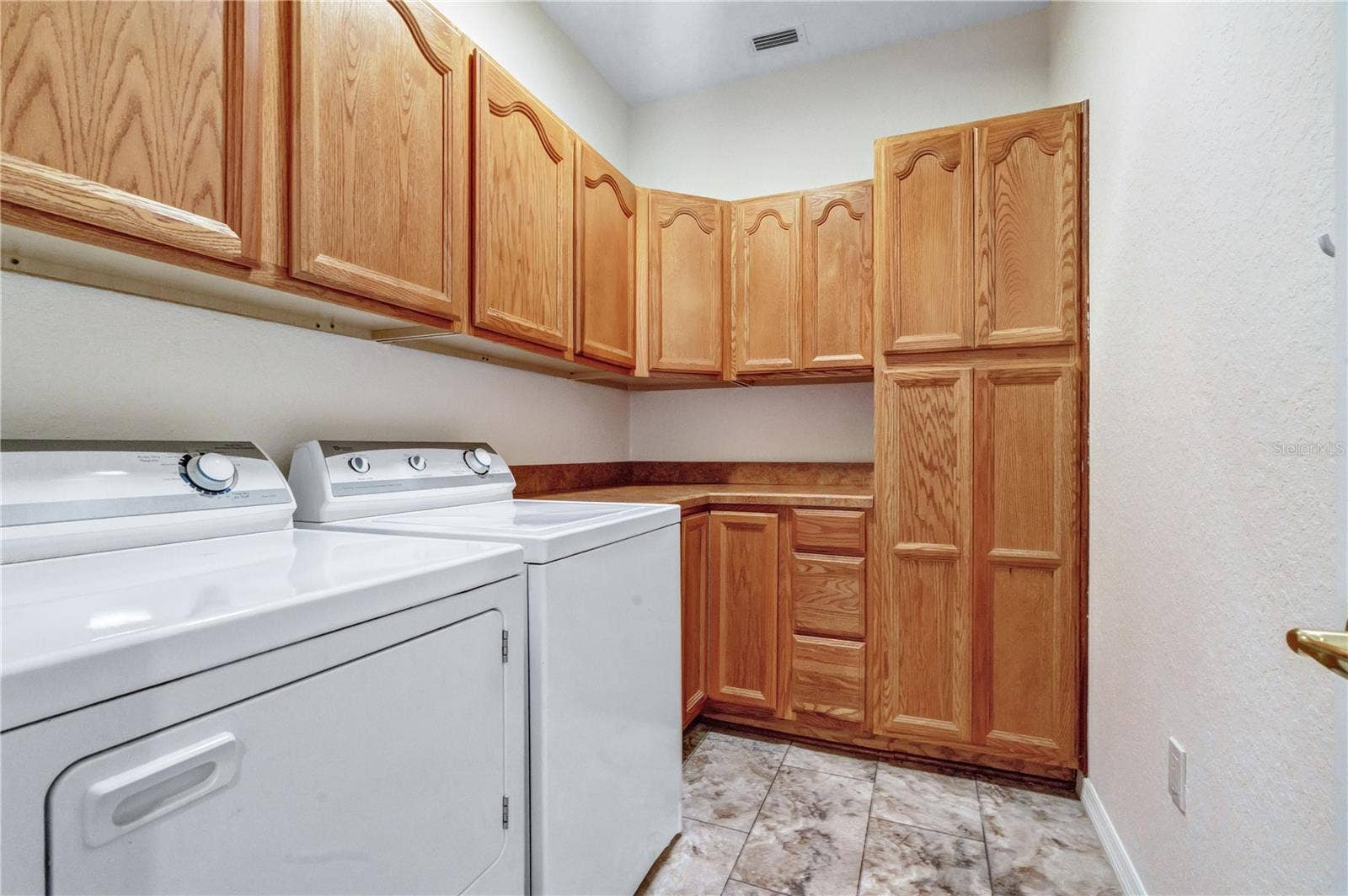 Convenient indoor laundry room with washer, dryer, abundant cabinetry, and countertop workspace.