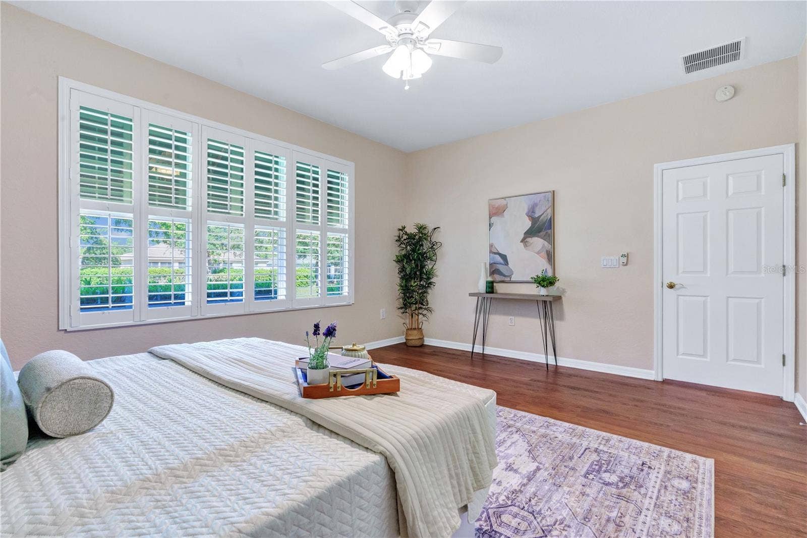 Light-filled primary bedroom with plantation shutters and a comfortable, spacious layout.