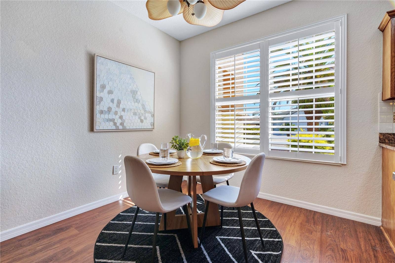 Charming dining nook with plantation shutters, abundant natural light, and beautiful wood-look flooring.