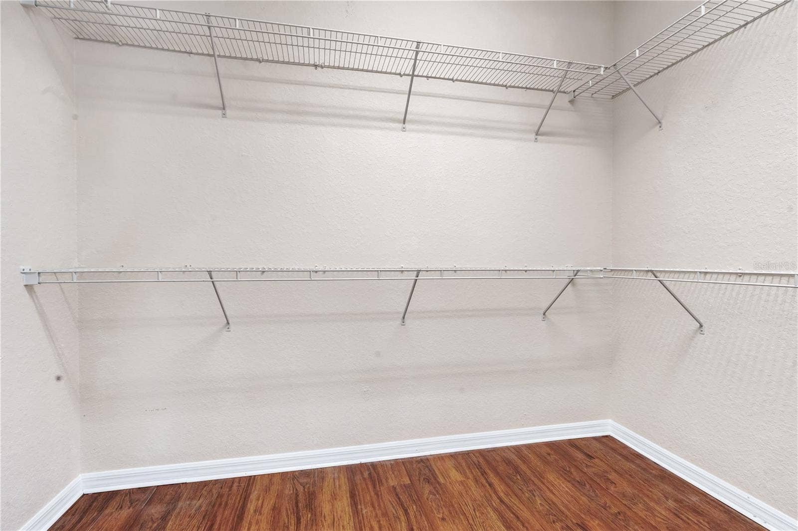 Generous walk-in closet with built-in shelving and hanging space for organized storage.