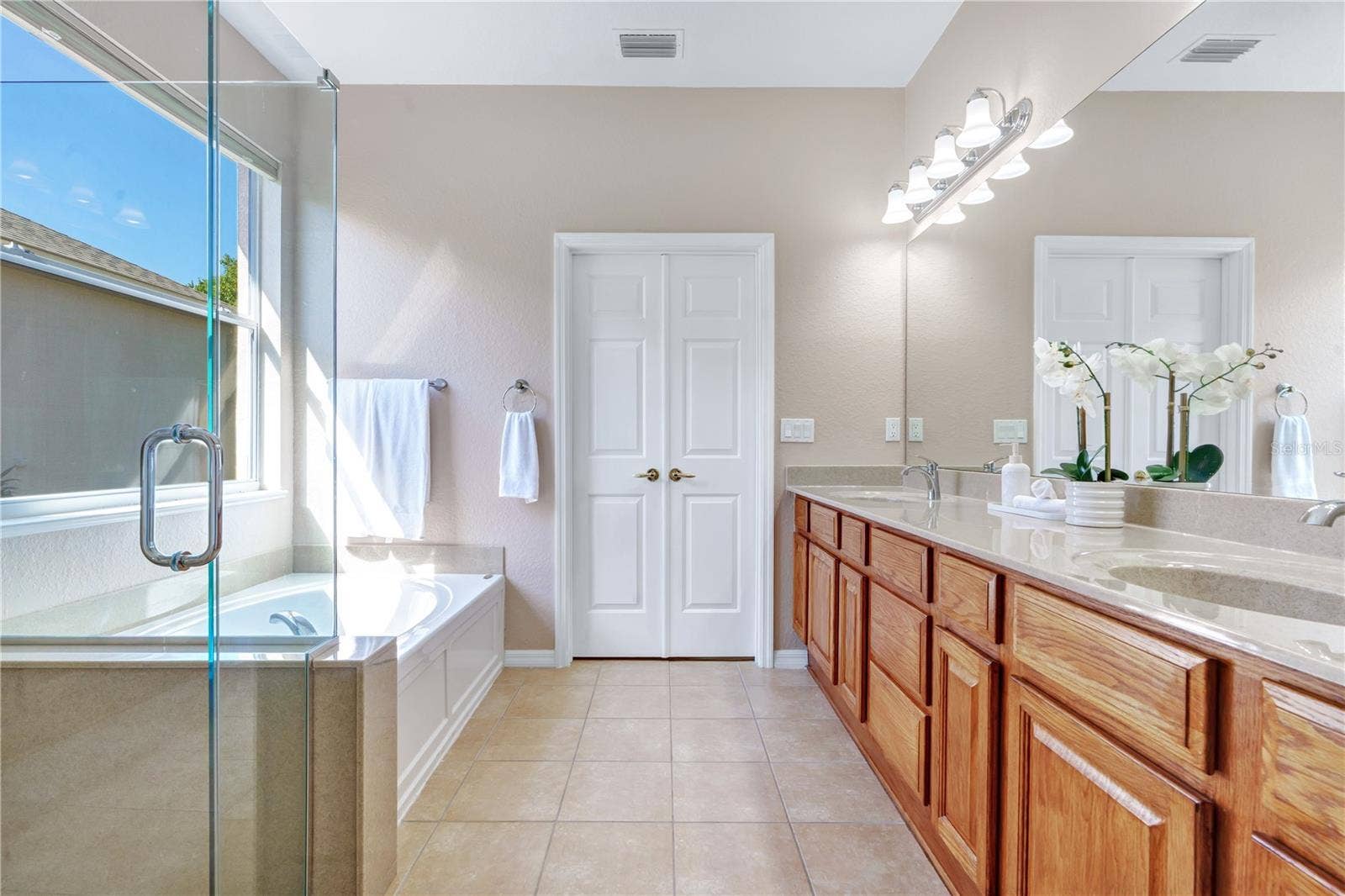 Expansive primary ensuite with dual vanities, generous counter space, separate shower, and soaking tub.