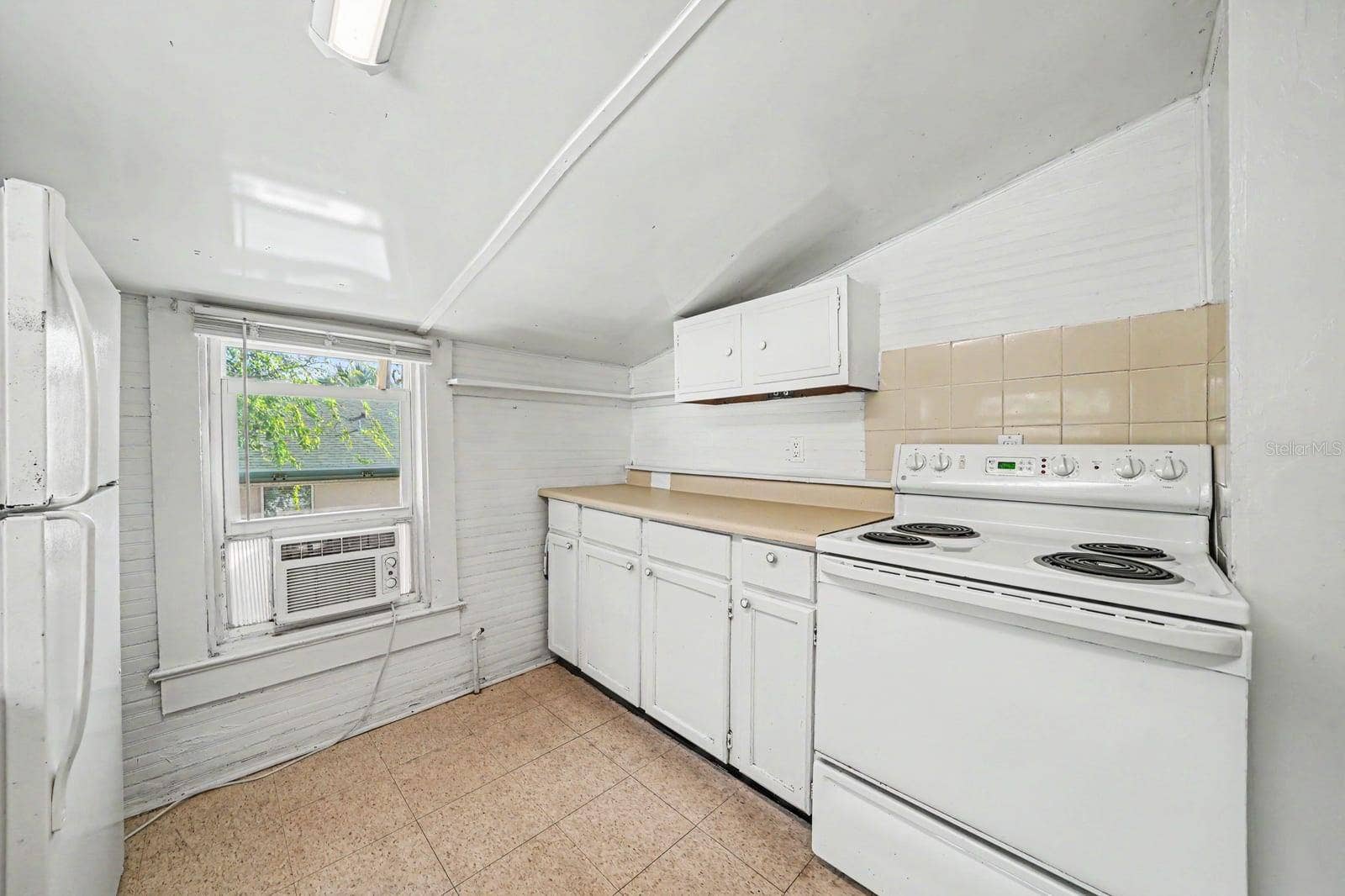 1015 S PENINSULA DRIVE, #1,2, Daytona Beach, FL 32118 Bright Kitchen with White Cabinetry, Tile Counters & Windows with Natural Light