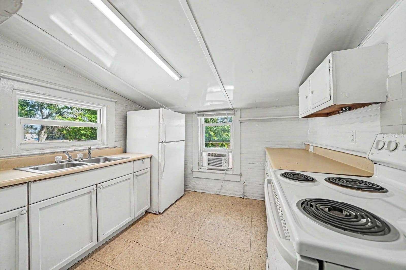 1015 S PENINSULA DRIVE, #1,2, Daytona Beach, FL 32118 Galley Kitchen with White Appliances, Coil Range & Window Overlooking Trees