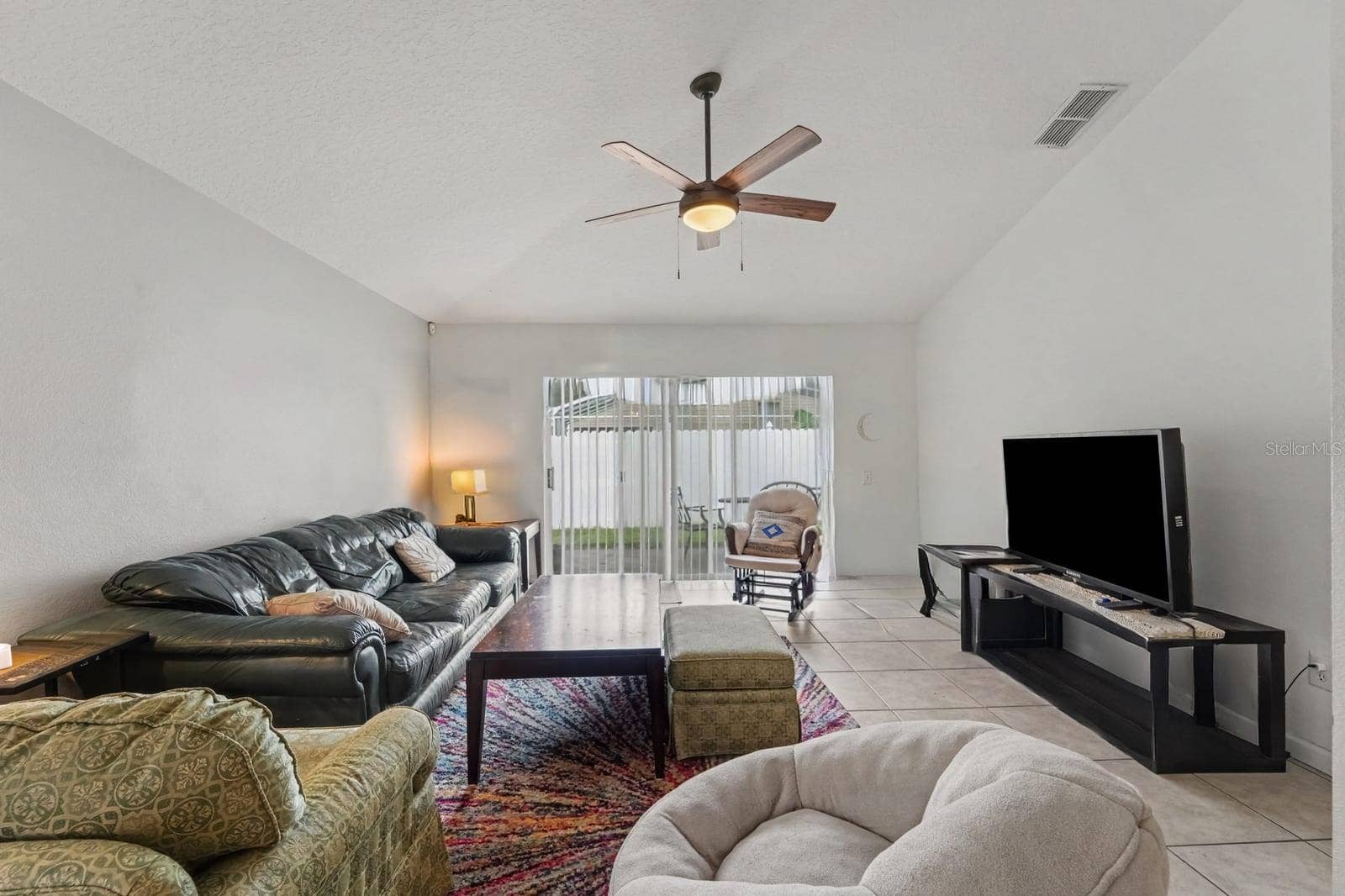 10913 BUCKWATER COURT, Orlando, FL 32817 Spacious living area with vaulted ceiling, tile flooring, and sliding glass patio doors