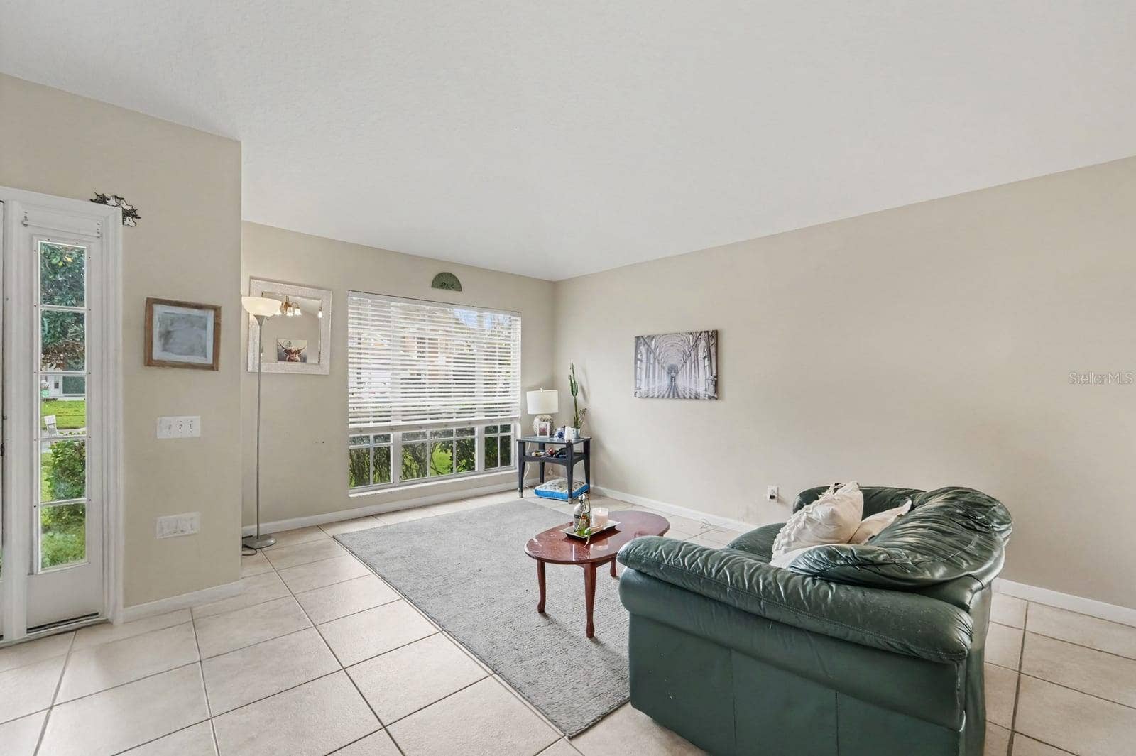 10913 BUCKWATER COURT, Orlando, FL 32817 Sunlit Sunroom with Sliding Glass Doors, Tile Flooring & Green Leather Seating