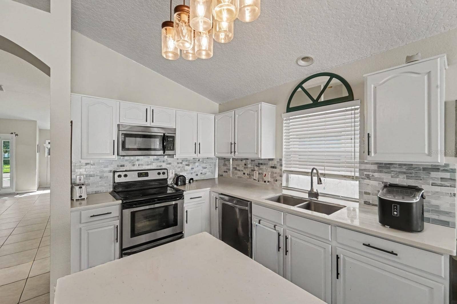 10913 BUCKWATER COURT, Orlando, FL 32817 Updated kitchen with white cabinetry, mosaic tile backsplash, and stainless appliances