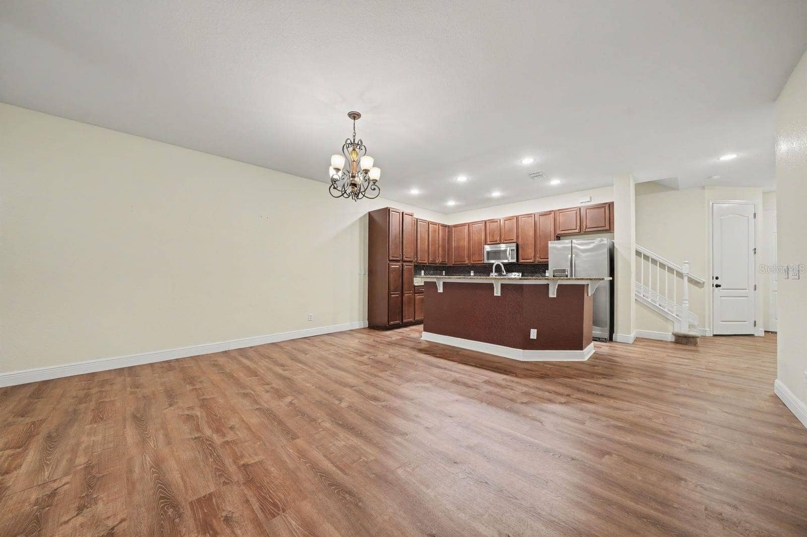Chef's Kitchen Features Wood Cabinetry, Island, And Granite Counters