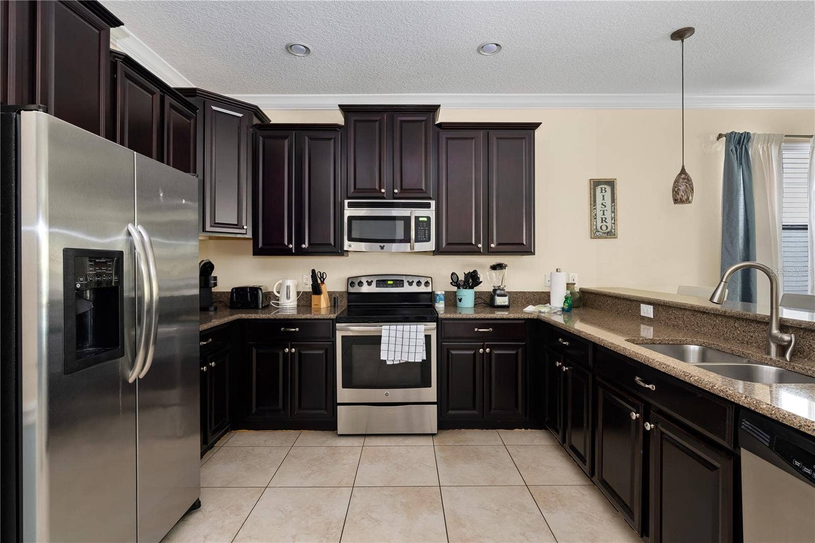 Spacious Kitchen Featuring Rich Espresso Cabinetry, Granite Countertops, Stainless Steel Appliances and Breakfast Bar Seating
