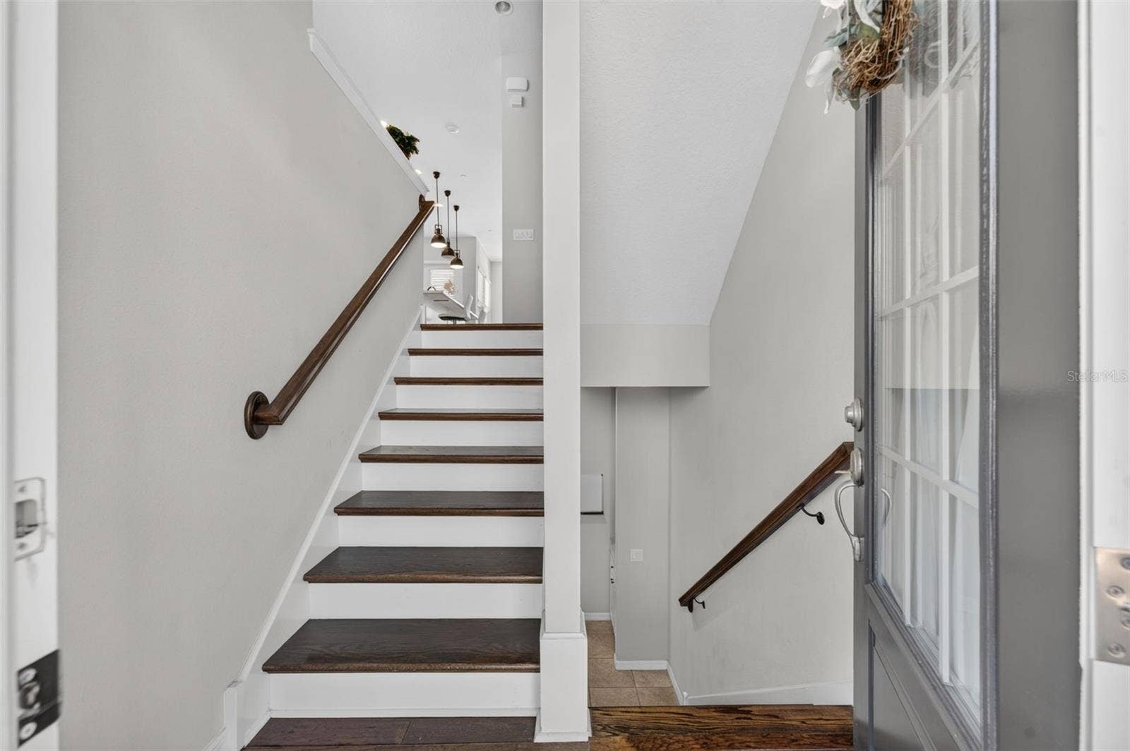 716 GRADO POINT, Oviedo, FL 32765 Stairwell upon entry; covered with hardwood flooring on all 3 stairways; short flight up goes to main living area; one short flight down there's a bedroom, full bath and garage entry. Top level has 2 Bedrooms, 2 full baths and a laundry room