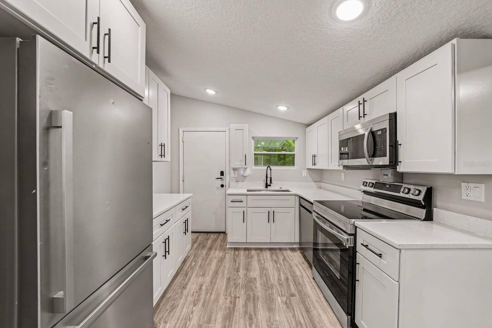 1611 SALMON STREET, St Cloud, FL 34771 Modern kitchen with white cabinetry, stainless appliances, and open layout