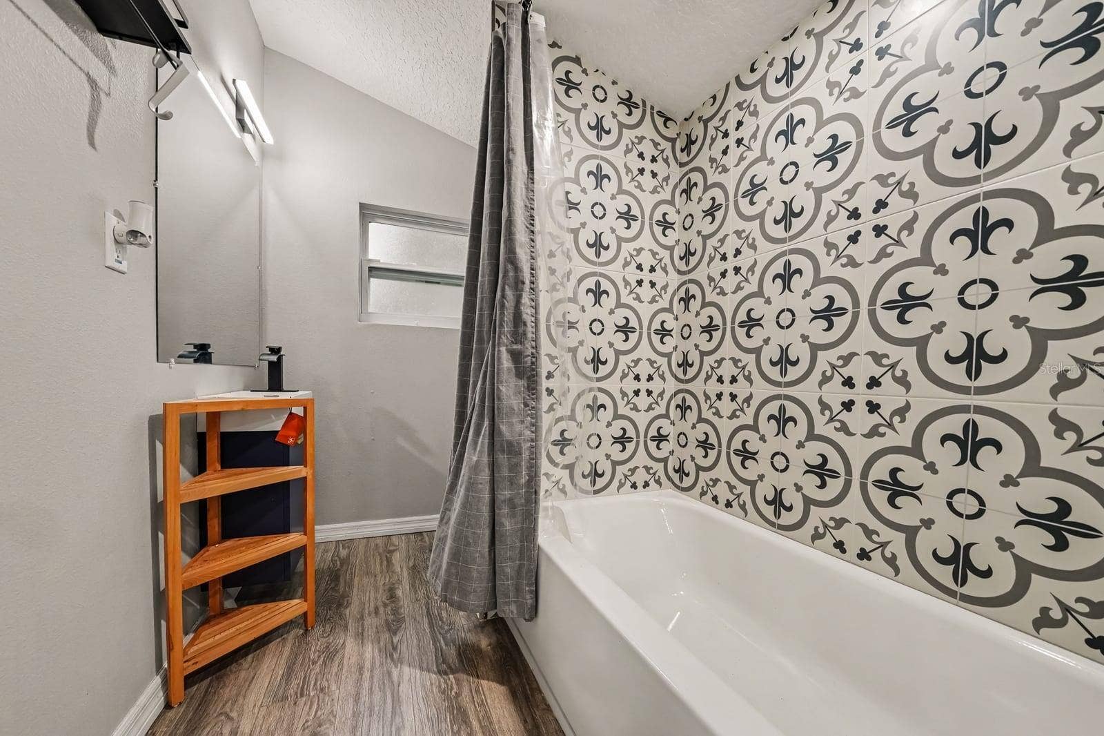 1611 SALMON STREET, St Cloud, FL 34771 Guest Bath Featuring Patterned Tile Accent Wall and Wood Shelving