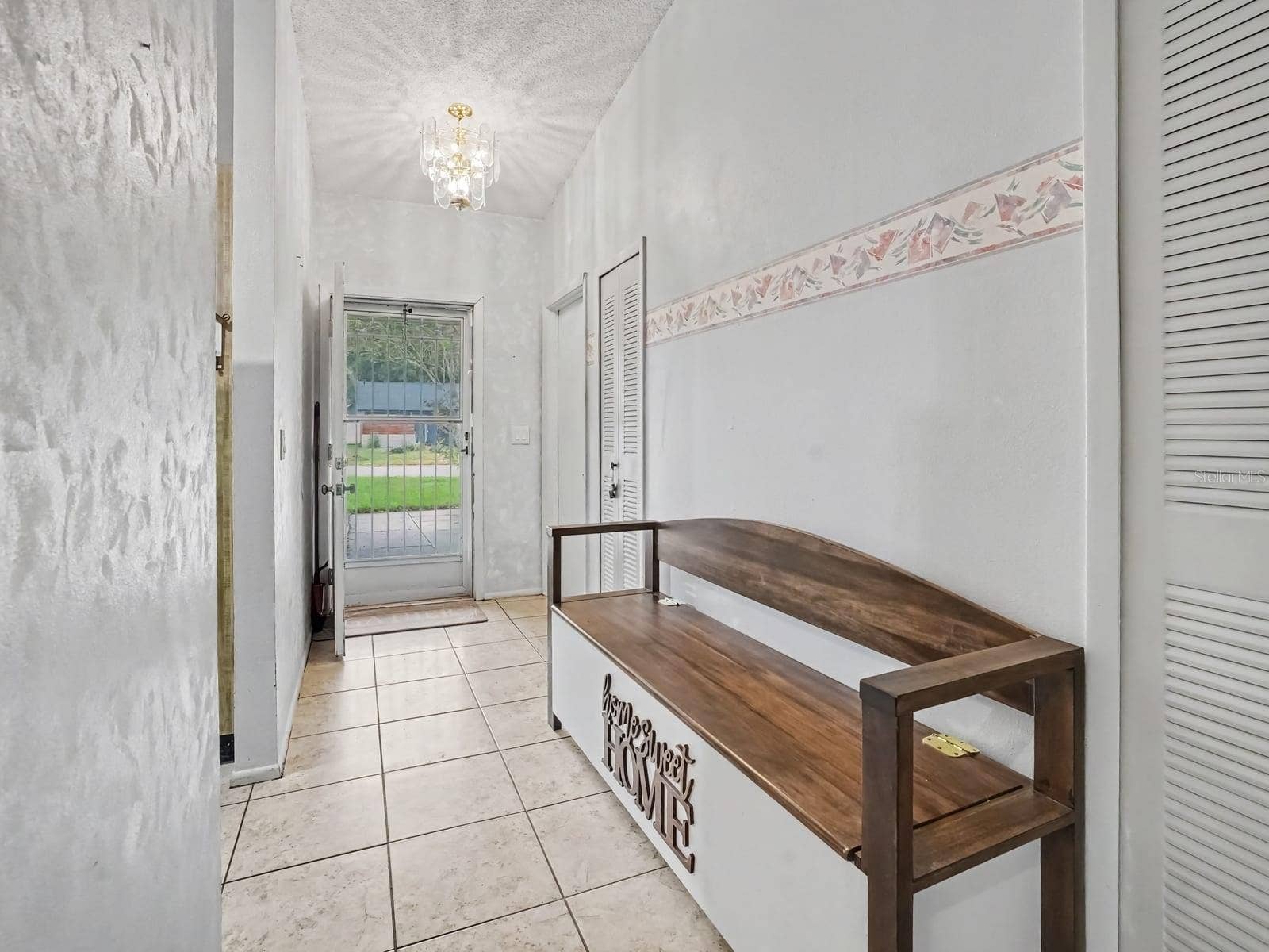Entryway with tile flooring, glass doors & decorative bench