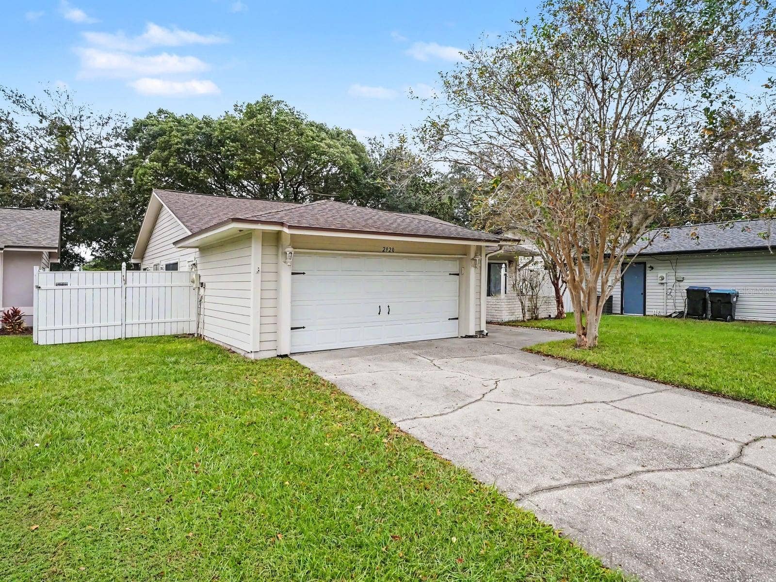 Single-story home with attached garage, white siding & landscaped lawn