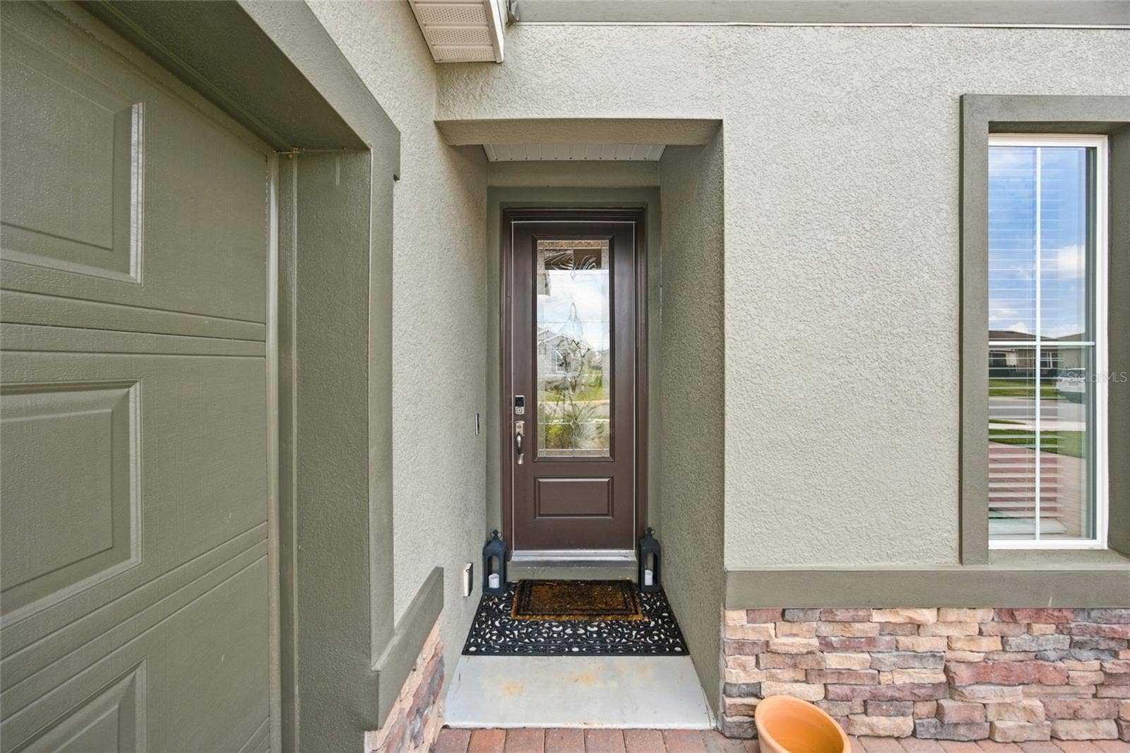 Recessed front entry with decorative glass front door and stone detailing.