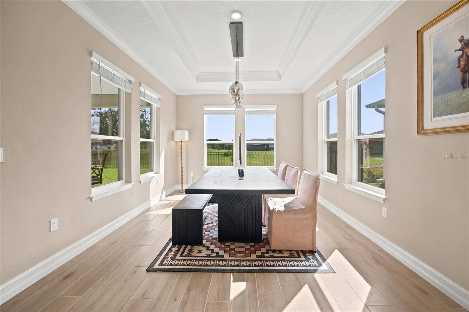 Bright dining room surrounded by windows with views toward the rear green space.