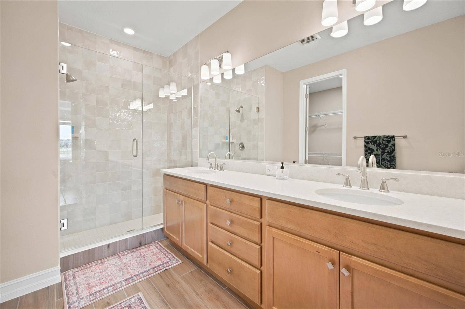 Primary bathroom featuring dual sinks, generous vanity space and a glass-enclosed shower.
