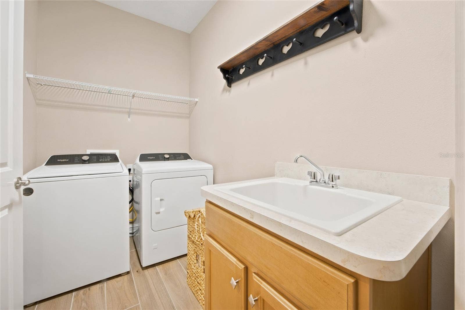 Interior laundry room with utility sink, cabinetry, washer and dryer.
