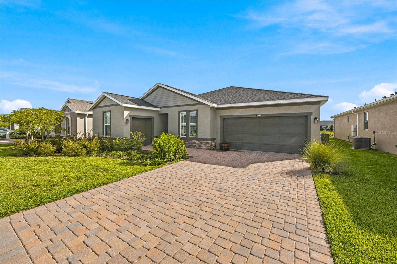 Angled exterior view highlighting the attractive paver driveway and landscaping.