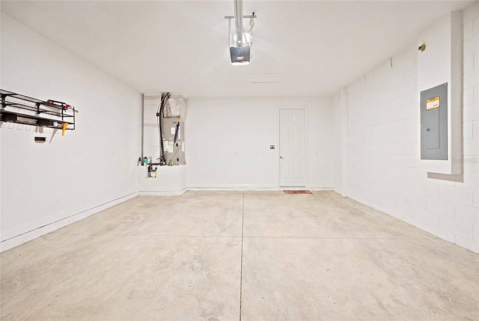 Two-car garage with concrete flooring and overhead storage rack.