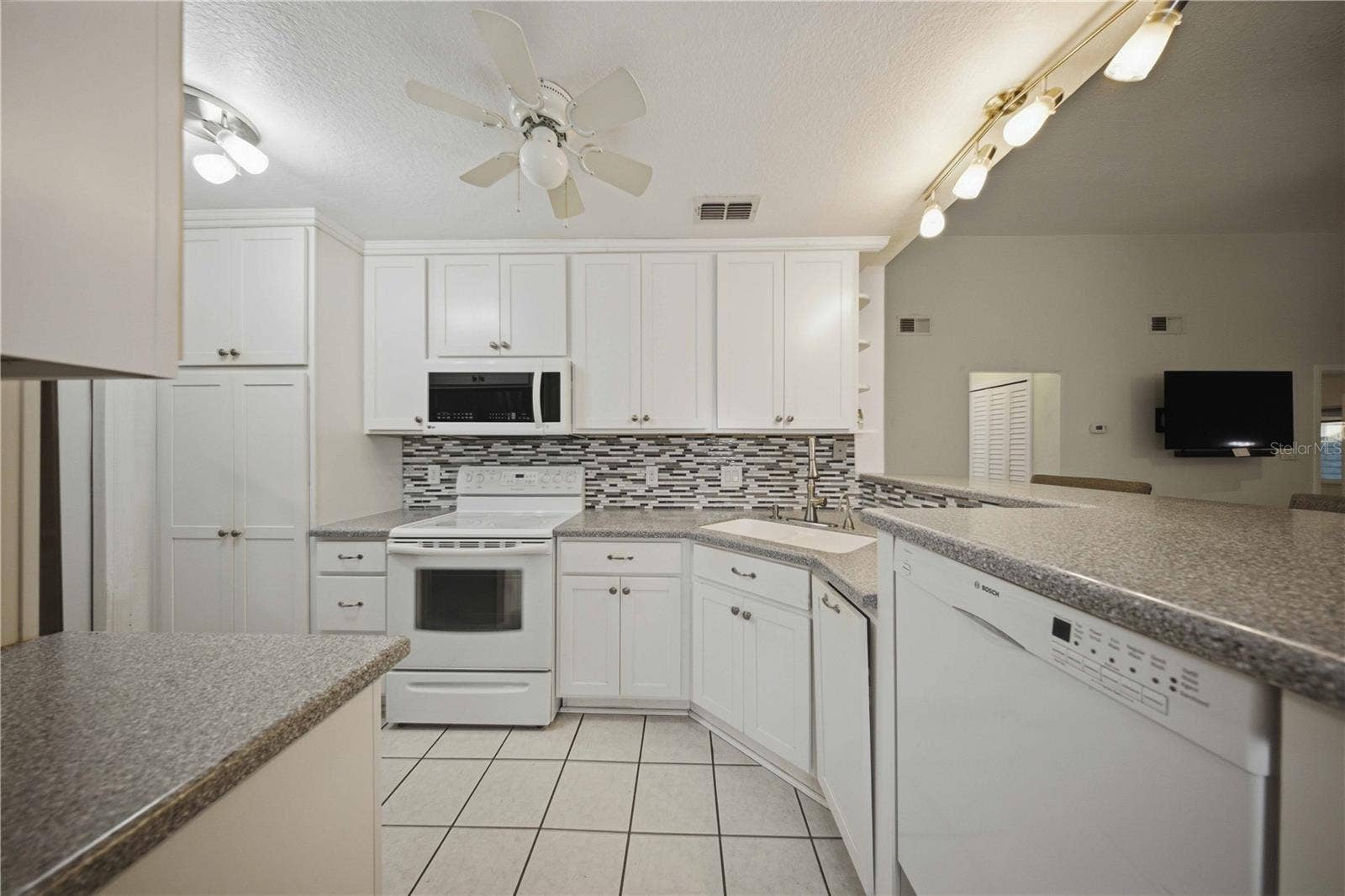 Updated kitchen with raised ceiling, 42" upper cabinets, corian counters, tile backsplash, and on demand instant hot water at sink!