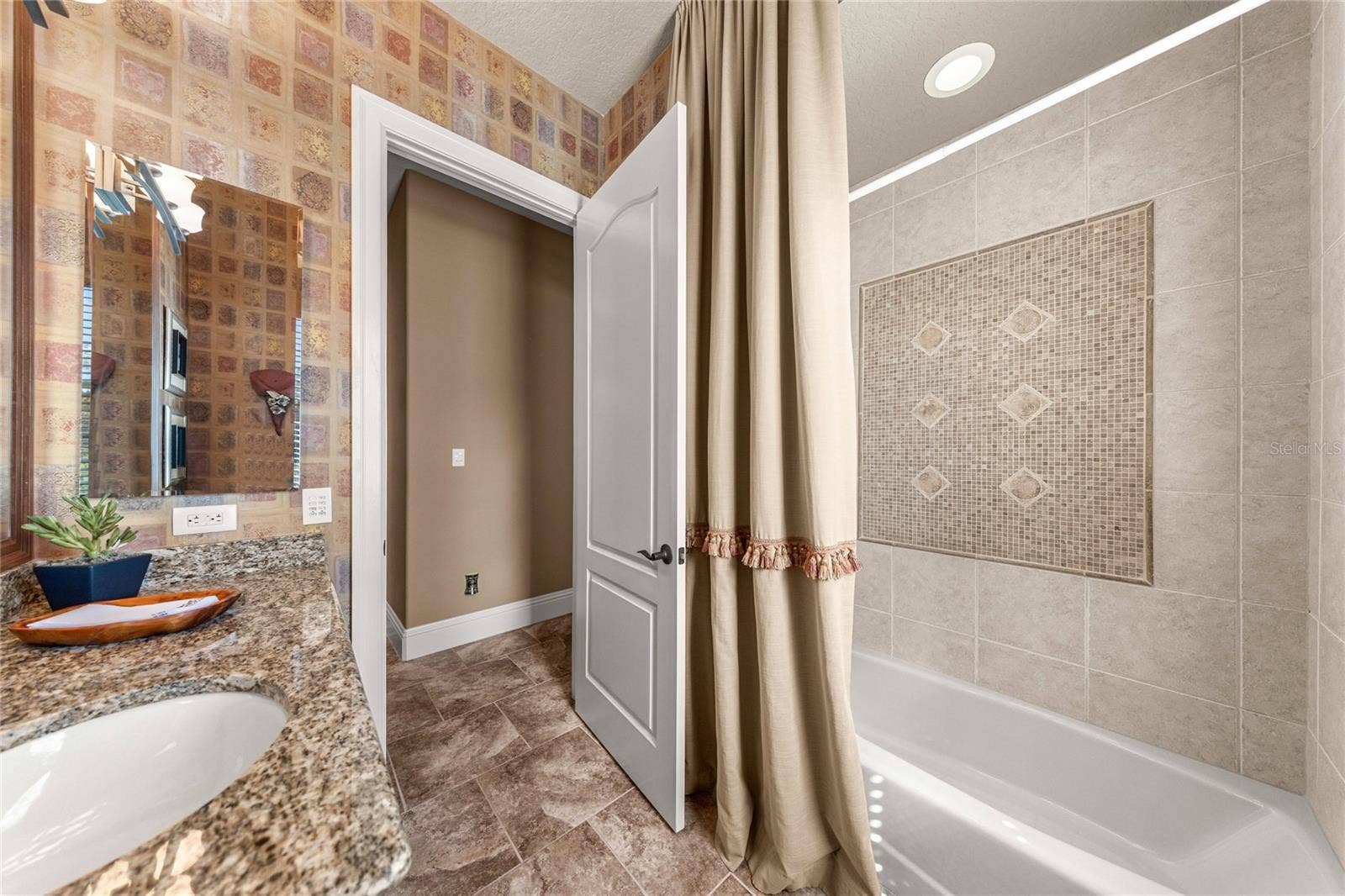 Tub and shower combination with decorative tile surround and accent detailing, offering both style and functionality.