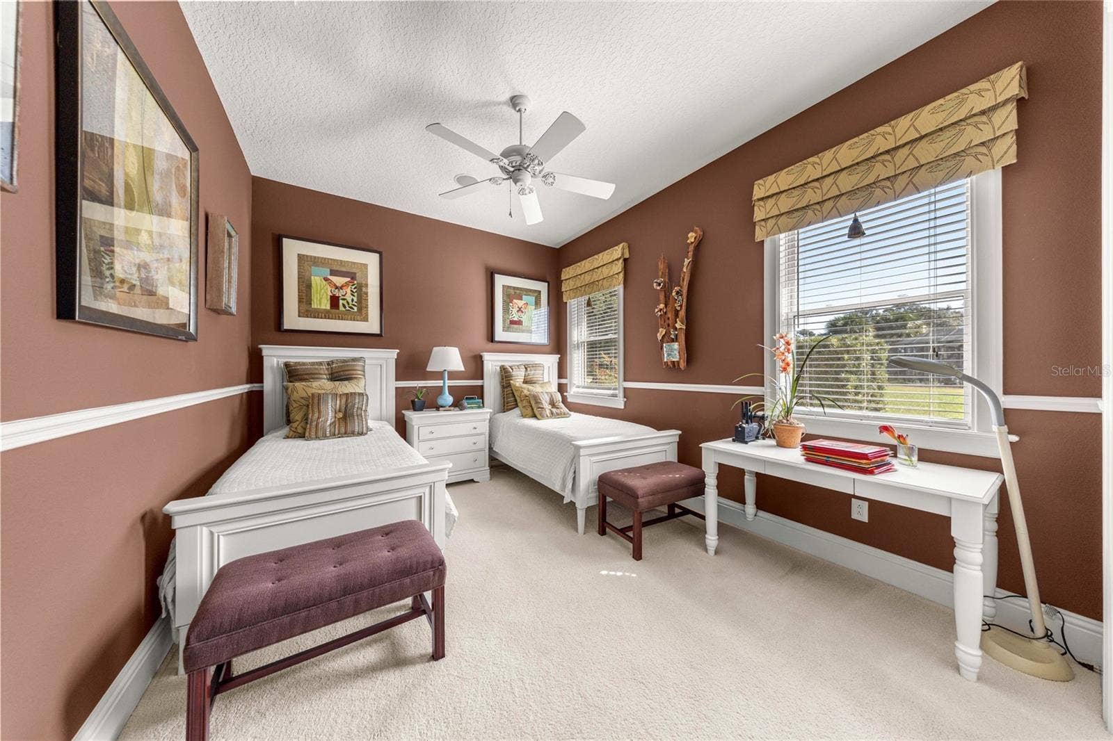 Spacious bedroom featuring two windows, ceiling fan, generous closet space, and room for a desk or study area.