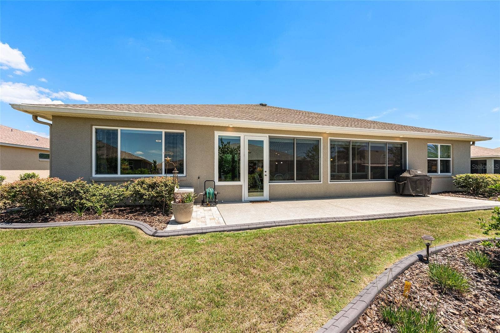 Full rear elevation showcasing the home's attractive architectural design, expansive windows, and generous outdoor living space. The extended patio and landscaped surroundings complement the home's spacious backyard setting.