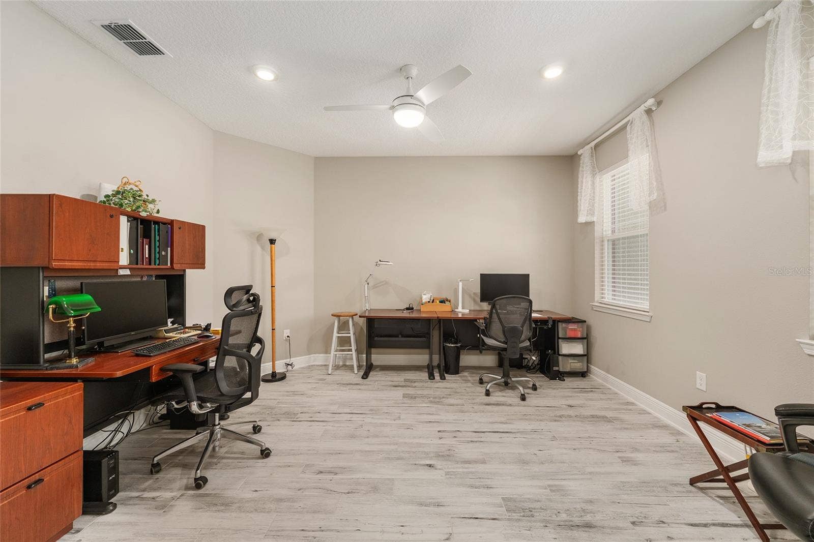 Generously sized flex room featuring ceramic plank flooring, neutral finishes, recessed lighting, and a ceiling fan with integrated lighting. Large windows bring in natural light, creating an inviting space for a home office, sitting room, or hobby room.