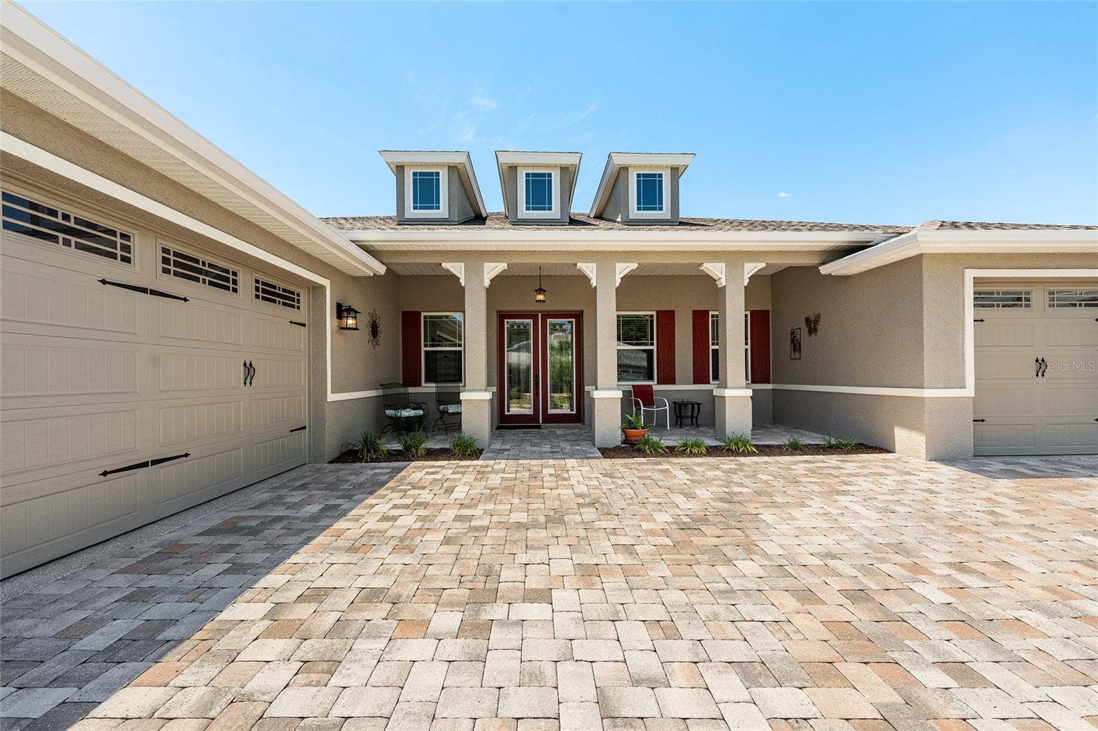 Beautiful 2021 Aberdeen model offering exceptional curb appeal with an expansive covered front porch, elegant leaded-glass double entry doors, attractive paver driveway, and professionally landscaped grounds that create a warm and welcoming first impression.