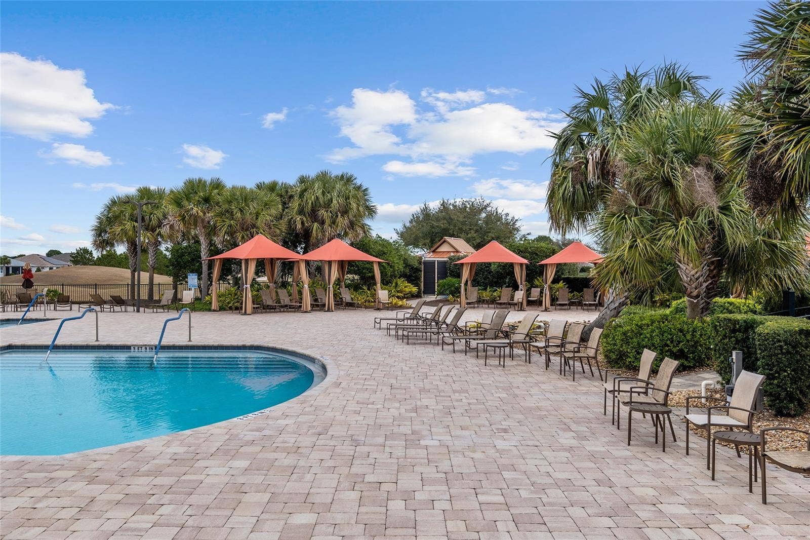 Relax poolside at Candler Hills, where inviting shaded cabanas, comfortable lounge seating, and lush tropical landscaping create a resort-inspired setting for unwinding, socializing, and enjoying the Florida sunshine.