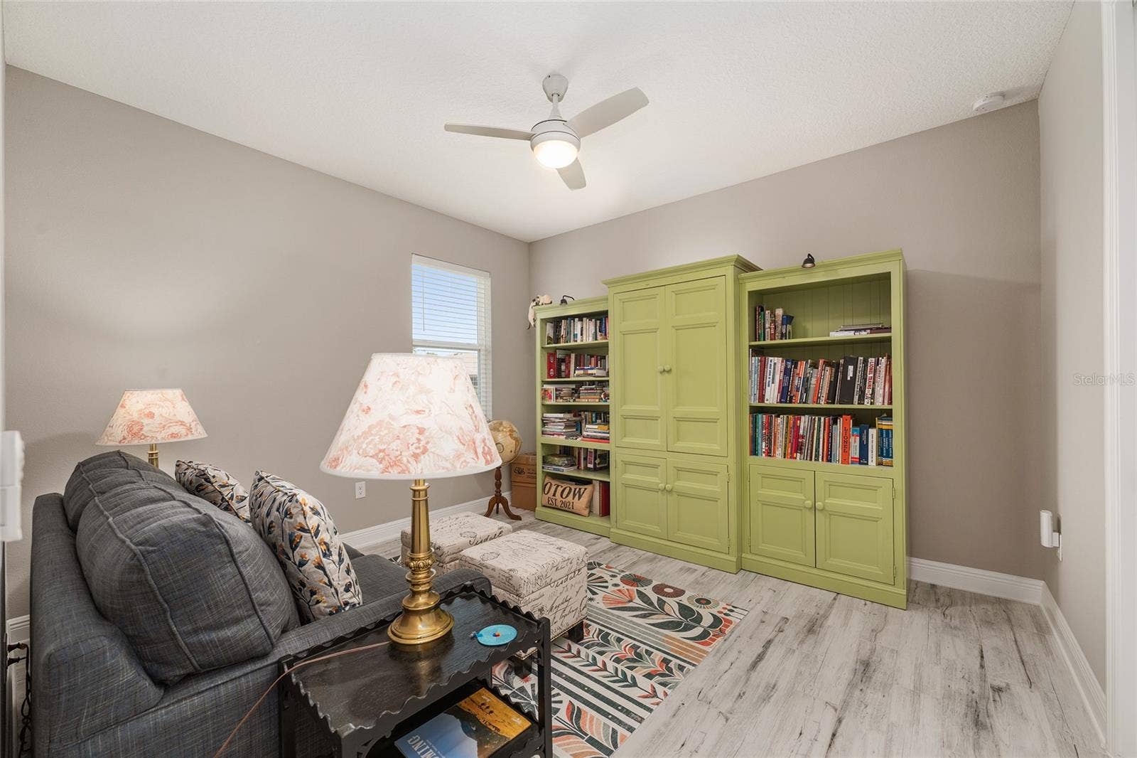 Comfortable third bedroom featuring ceramic plank flooring, ceiling fan with light, neutral finishes, and natural light.currently used as a den