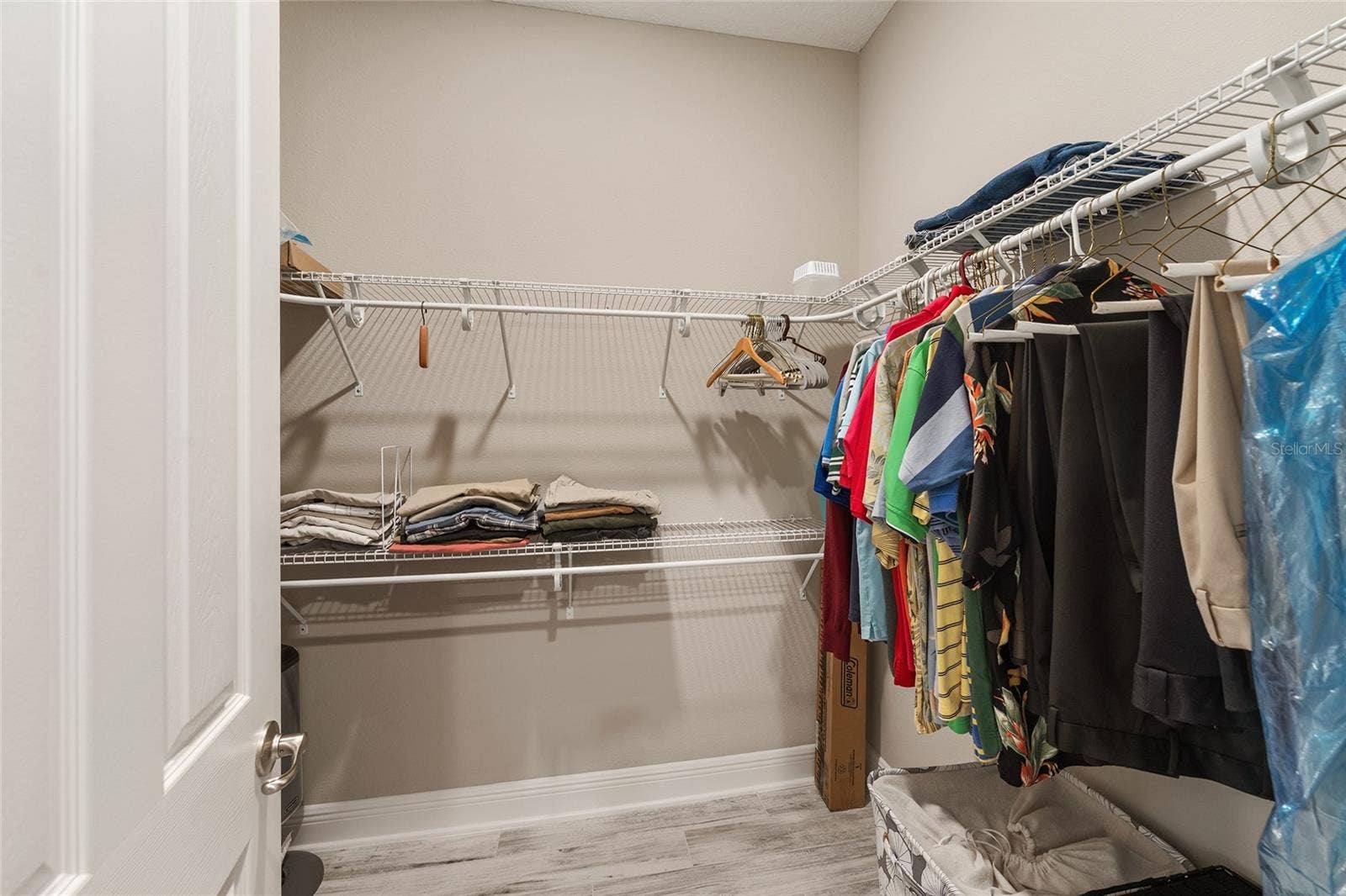 First of two walk-in closets in the primary suite, featuring wraparound shelving and generous hanging space for convenient storage and organization.