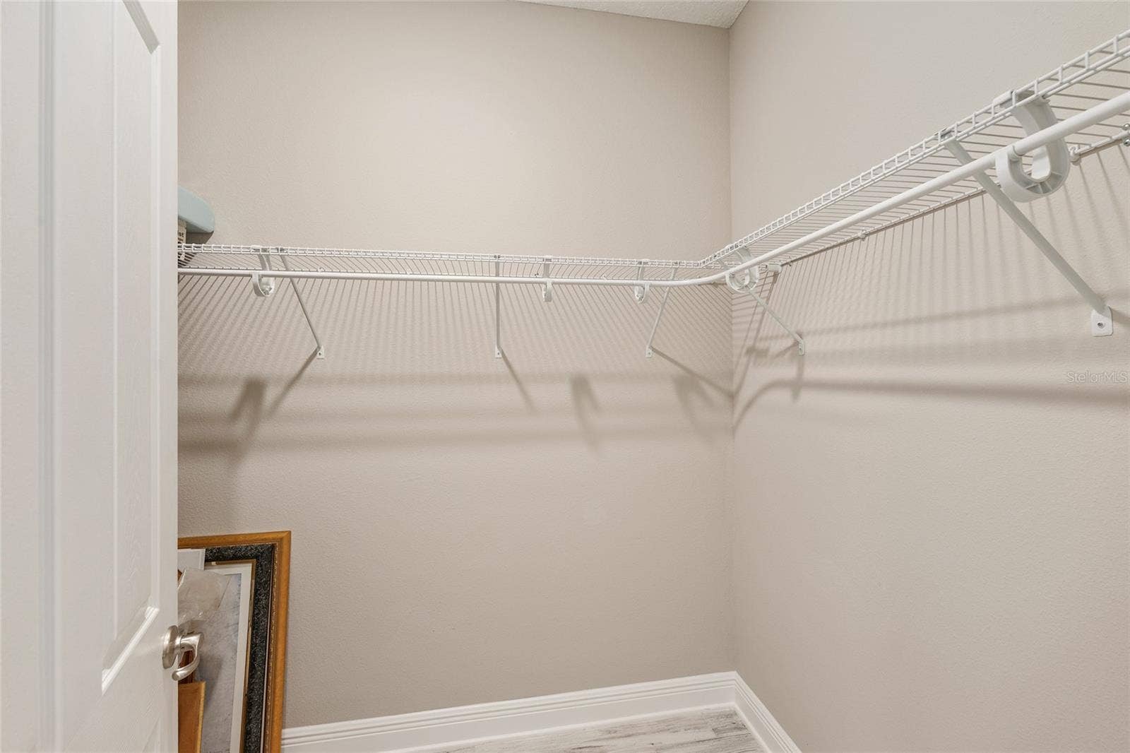 Second primary suite's spacious walk-in closet features wraparound shelving and ample hanging space, providing practical storage and organization.
