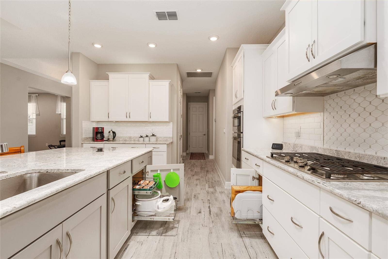 Thoughtfully designed kitchen featuring a large single-basin sink with built-in soap dispenser, convenient pull-out storage organizers, Cambria quartz countertops, and a decorative tile backsplashcombining functionality with everyday convenience.