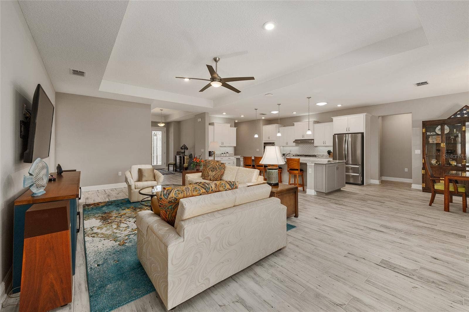 Designed for comfortable living and effortless entertaining, this spacious open floor plan showcases neutral finishes, ceramic plank flooring, elegant tray ceilings, upgraded hardware, dovetail drawers, and ceiling fans with integrated lighting, creating a warm and inviting atmosphere throughout.