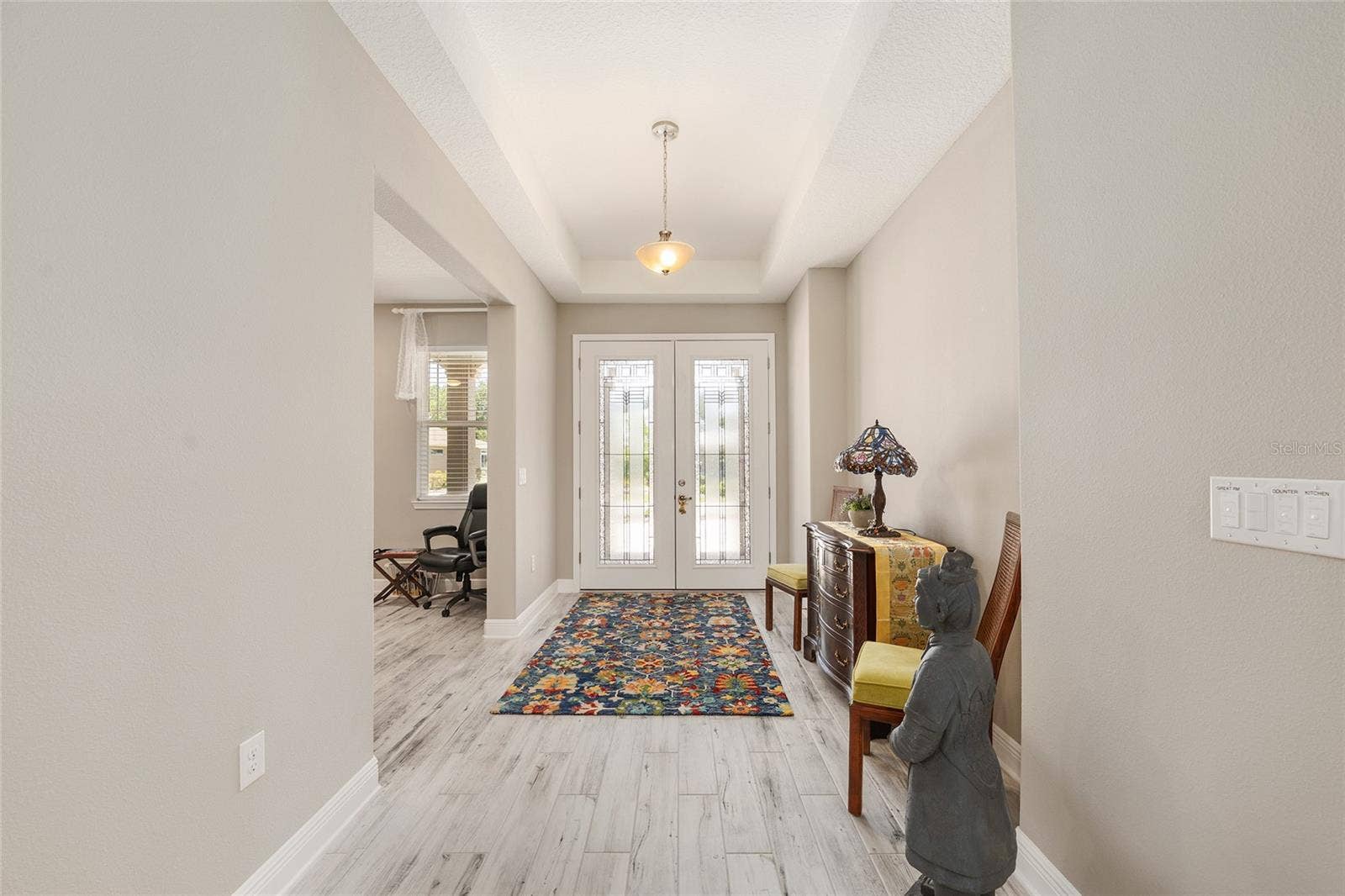 Spacious foyer with an elegant tray ceiling and a welcoming layout, offering a glimpse into the versatile flex roomperfect for a home office, sitting room, or quiet retreat.