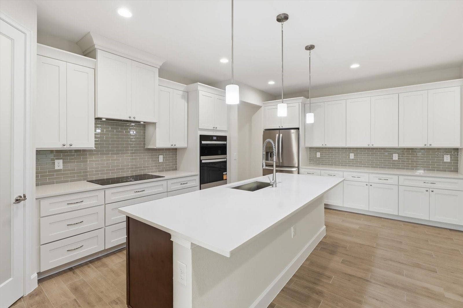 The chefs kitchen features an oversized quartz island, walk in pantry, crown molding and upgraded 4 door refridgerator.