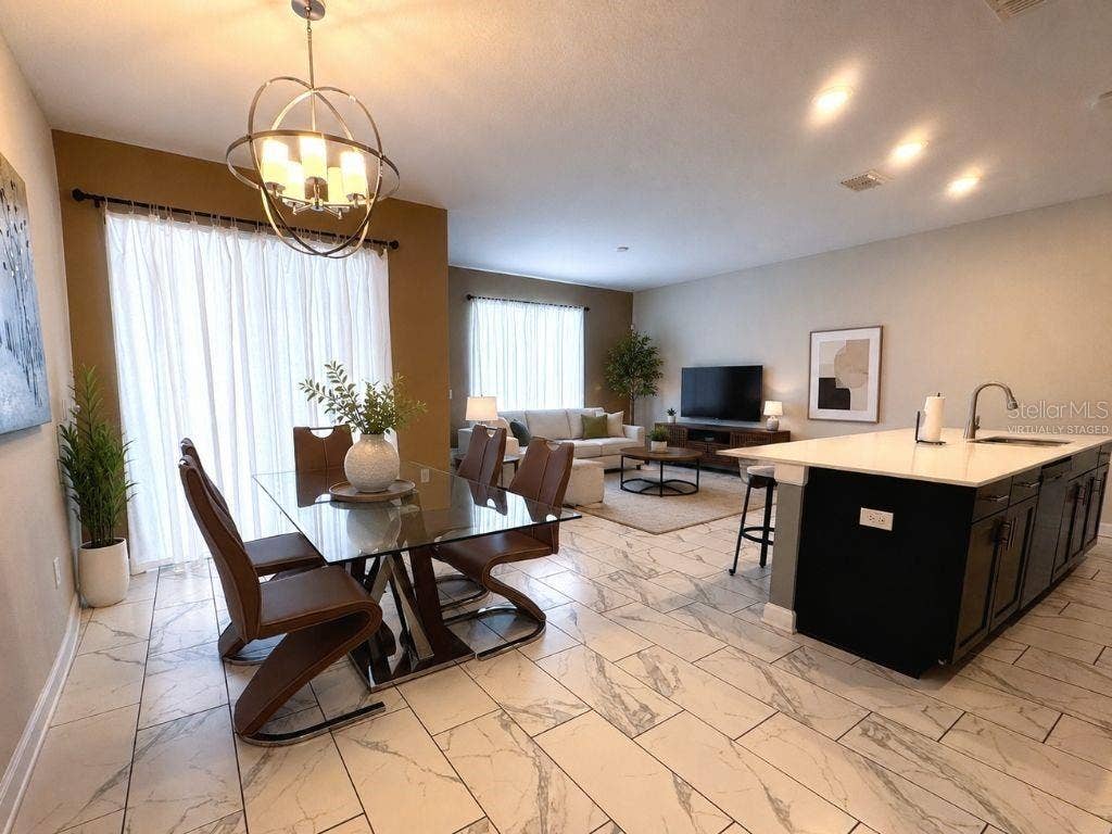 Virtually staged open-concept living, dining, and kitchen area showcasing the homes bright layout, stylish finishes, and comfortable gathering spaces.