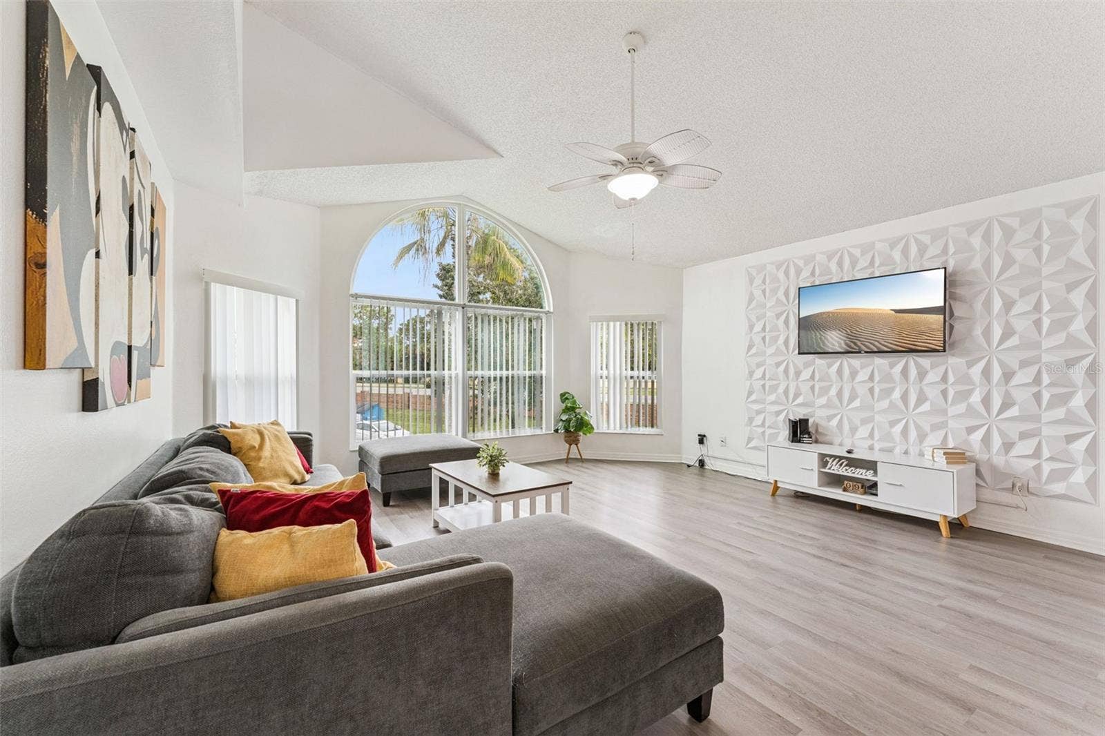 5017 LAGUNA BAY CIRCLE, #100, Kissimmee, FL 34746 Living Room Alternate View: View of the main living area showcasing the custom 3D accent wall, media console, wall-mounted TV, and spacious layout.