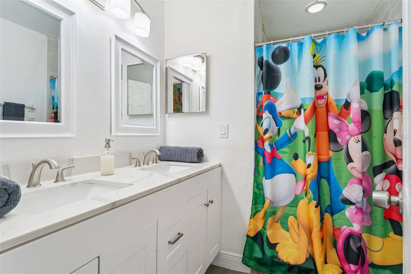 5017 LAGUNA BAY CIRCLE, #100, Kissimmee, FL 34746 Guest Bathroom Double Vanity: Guest bathroom featuring a crisp white vanity, modern stone-look countertop, dual sinks, and framed mirrors.