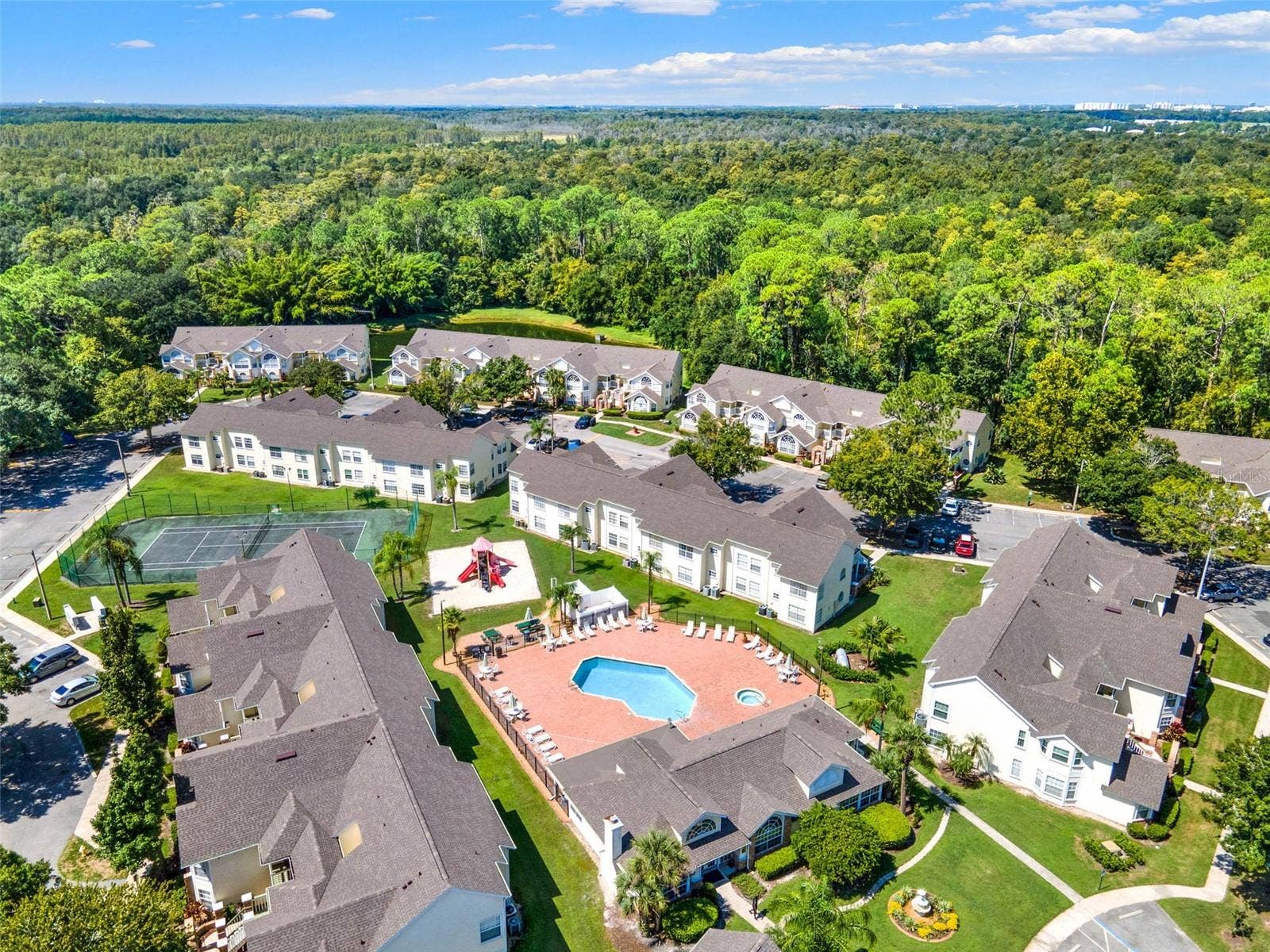 5017 LAGUNA BAY CIRCLE, #100, Kissimmee, FL 34746 Pool & Amenity Deck Aerial: Close-up aerial view centered on the resort-style swimming pool, heated spa, sunbathing patio, playground, tennis court, and clubhouse.