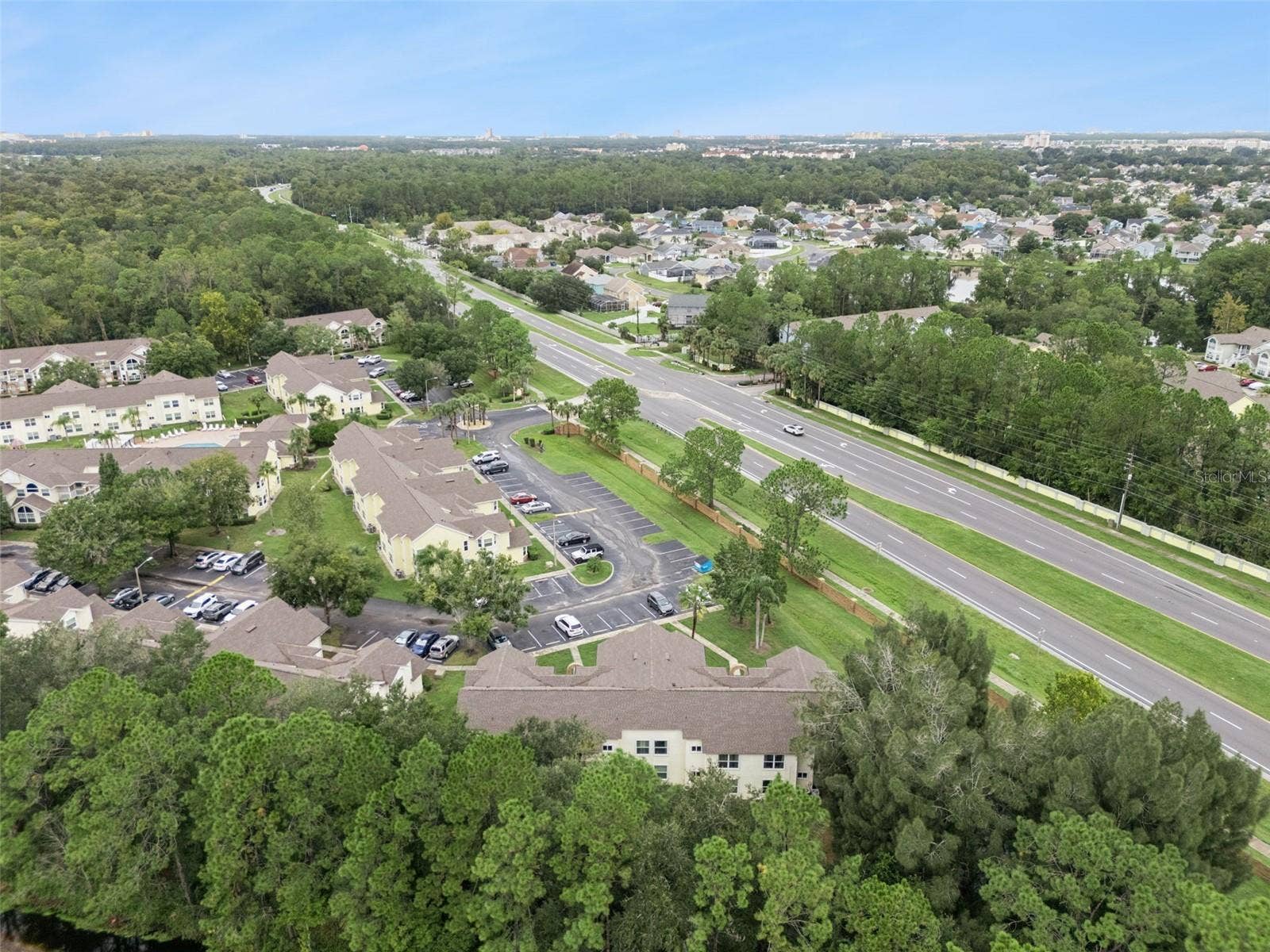 5017 LAGUNA BAY CIRCLE, #100, Kissimmee, FL 34746 Regional Aerial Perspective: High-altitude aerial view highlighting the property's convenient position along major local roadways surrounded by mature greenery.