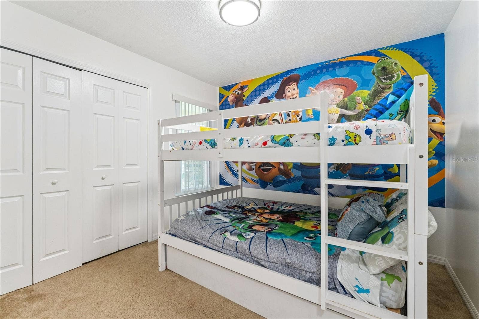 5017 LAGUNA BAY CIRCLE, #100, Kissimmee, FL 34746 Character Bunk Room View: Alternate angle of the bunk bedroom showcasing double bi-fold closet doors and colorful themed wall graphics