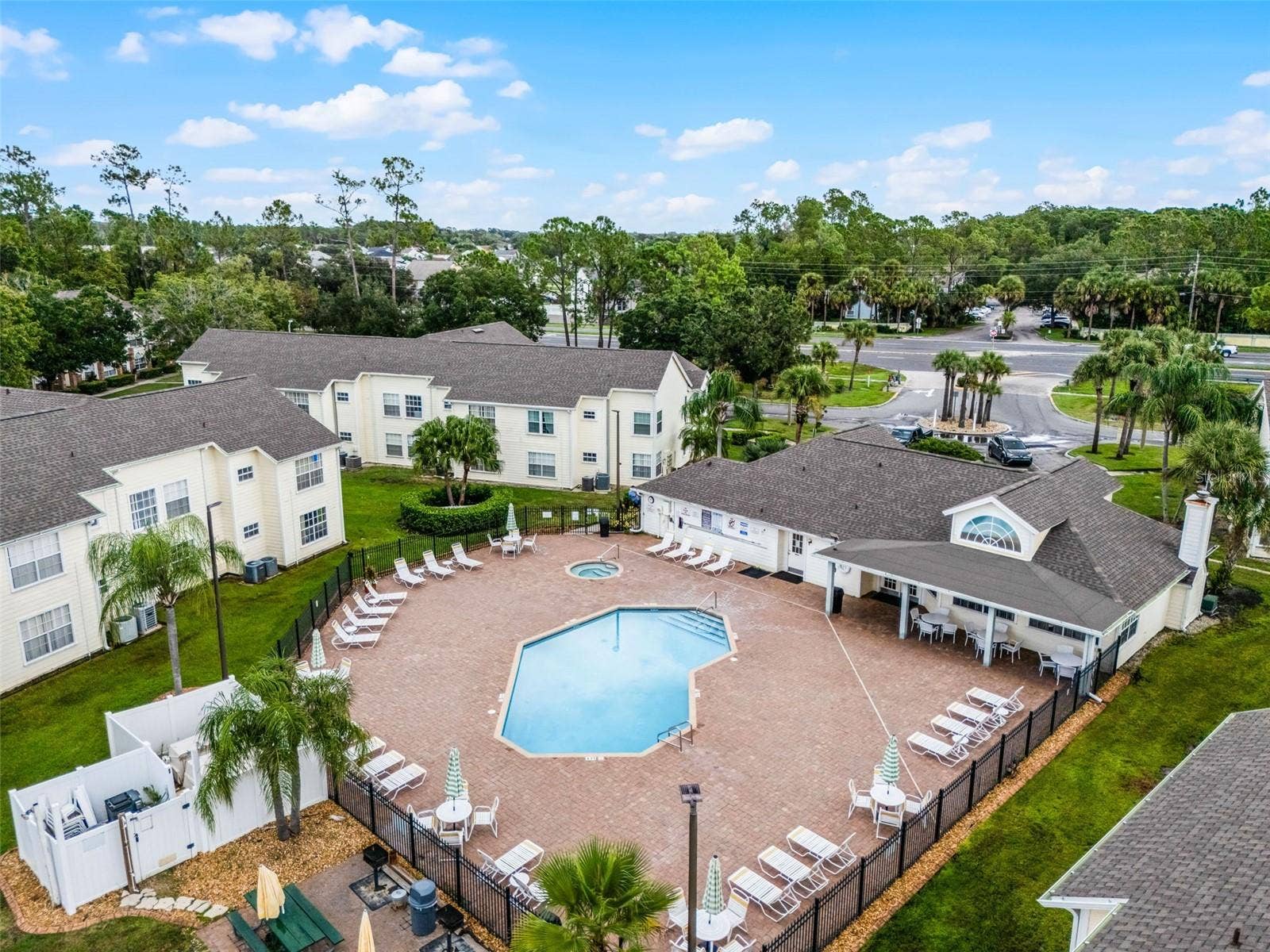 5017 LAGUNA BAY CIRCLE, #100, Kissimmee, FL 34746 Clubhouse & Pool Grounds: Aerial perspective featuring the community clubhouse, covered poolside pavilion, spacious sun deck, and surrounding residential villas