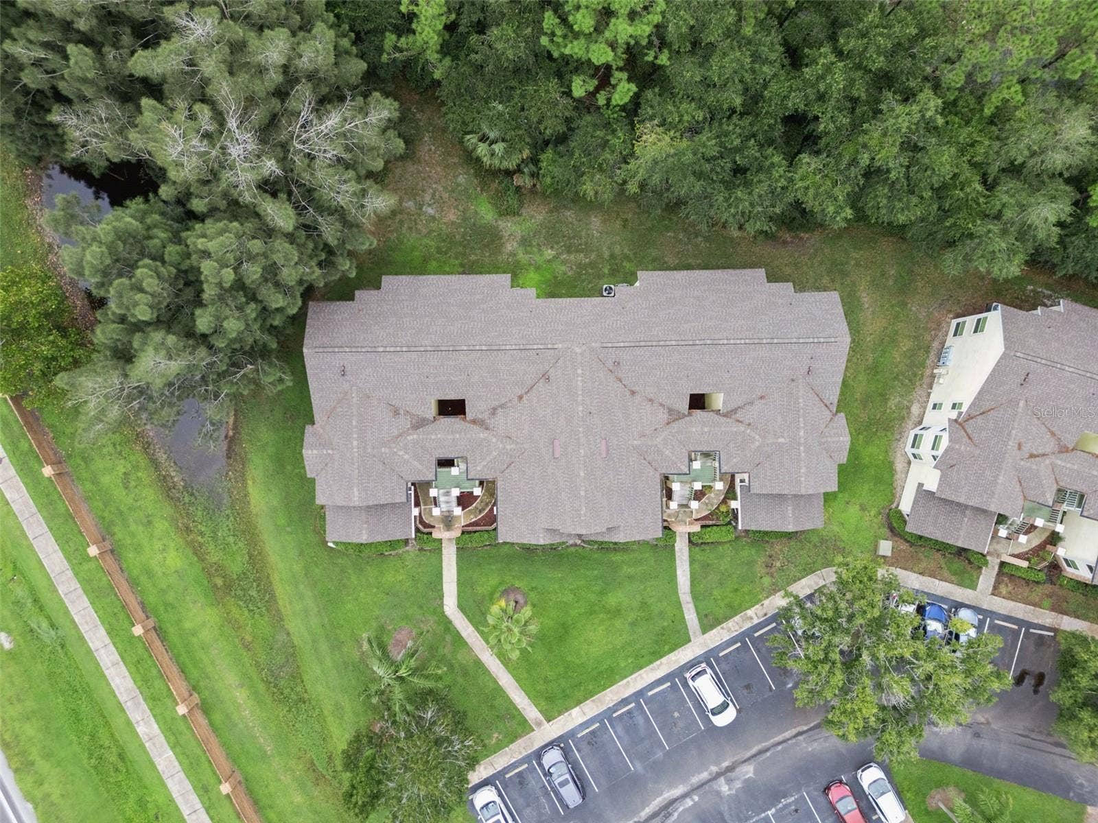 5017 LAGUNA BAY CIRCLE, #100, Kissimmee, FL 34746 Top-Down Aerial View: Direct overhead drone perspective highlighting the building roofline, front entryway paths, and mature tree borders