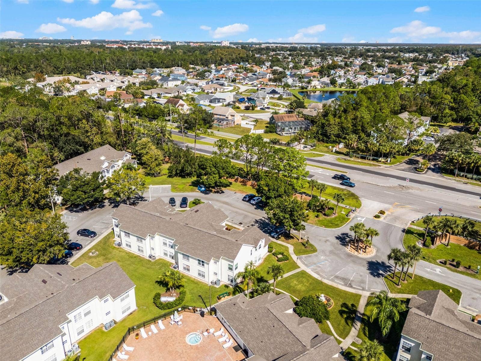 5017 LAGUNA BAY CIRCLE, #100, Kissimmee, FL 34746 Entrance & Pool Area Aerial: Aerial view highlighting the community entrance loop, ample resident parking, clubhouse pool deck, and surrounding local neighborhood.