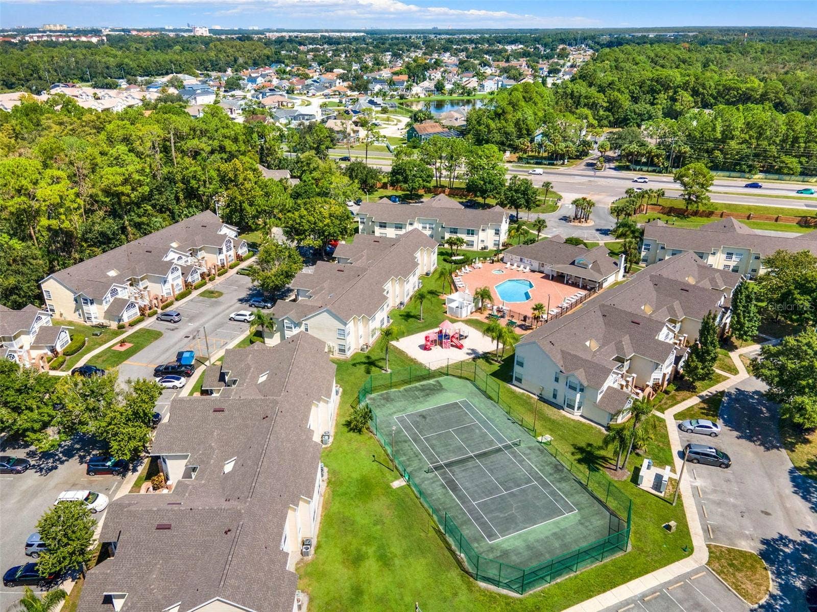 5017 LAGUNA BAY CIRCLE, #100, Kissimmee, FL 34746 Recreational Facilities Aerial: Elevated aerial view highlighting the outdoor tennis court, resort pool complex, playground area, and manicured green spaces.